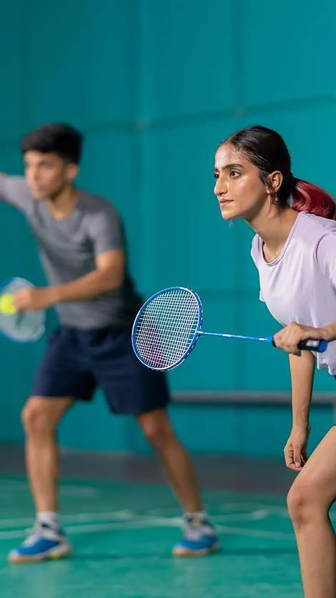 A mixed doubles pair waits at the net, rackets ready